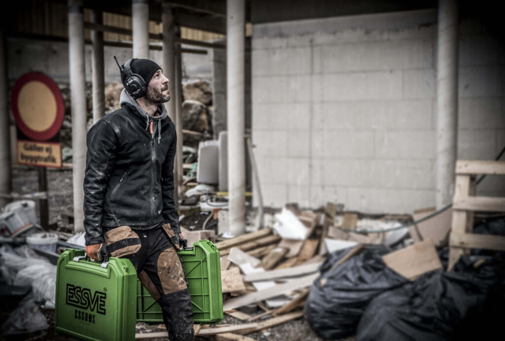 man carrying two essbox system cases through a site